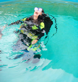 High angle view of woman scuba diving while laughing in swimming pool