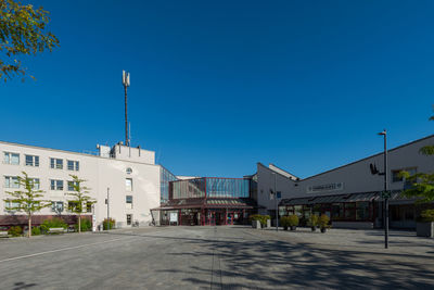 Street by buildings against clear blue sky