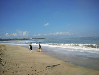 Two people walking on calm beach