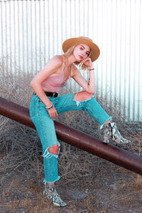 Portrait of young woman standing by railing