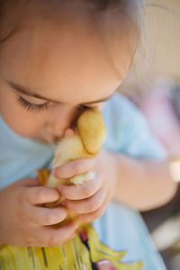 Little girl holding a yellow duckling in her hands.