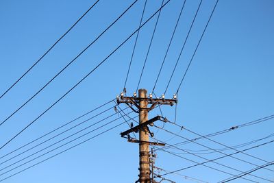 Low angle view of power line against blue sky