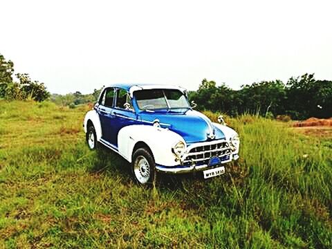 VINTAGE CAR ON GRASS AGAINST SKY