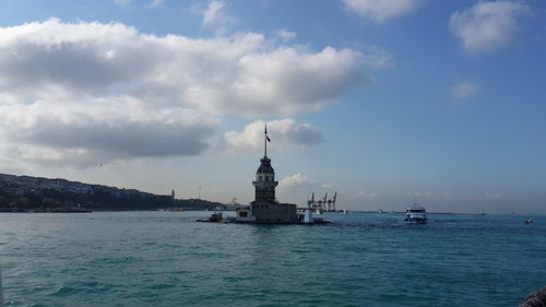 Statue in sea against cloudy sky