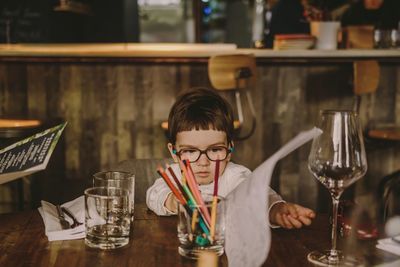 Portrait of man drinking glass on table at restaurant