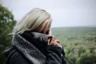 Portrait of woman wearing hat against sky during winter