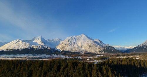 Scenic view of snowcapped mountains against blue sky