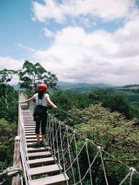 Rear view of woman standing on footbridge