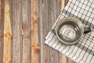 An empty cup that made from clear glass and plastic handle on a wooden background