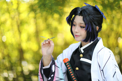 Young woman holding dragonfly outdoors