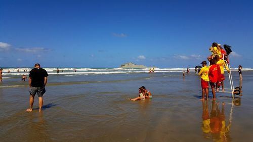 Rear view of people at beach against sky