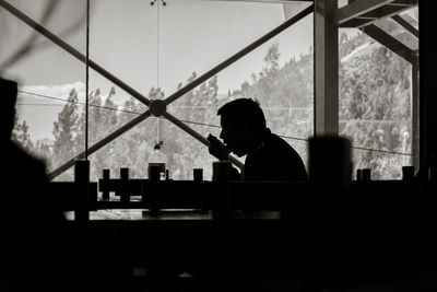 Side view of silhouette man drinking glass window