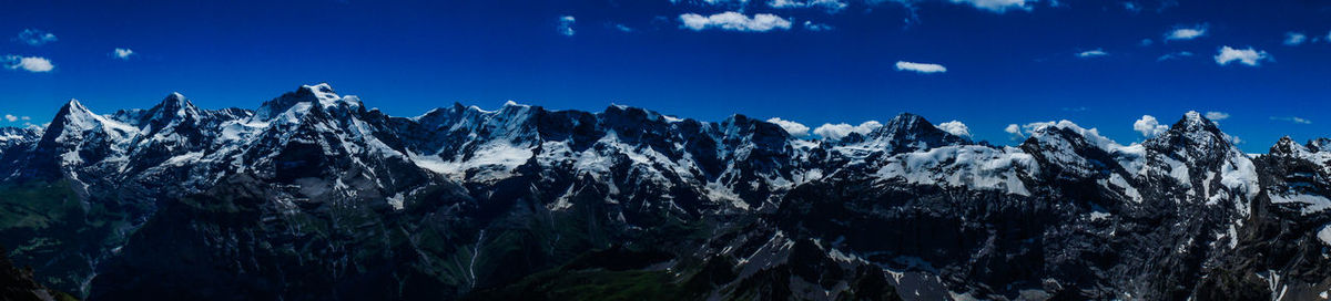 Panoramic view of snowcapped mountains against blue sky
