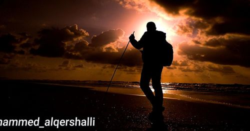 Silhouette man standing on beach against sky during sunset