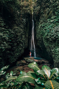 Woman standing amidst rocks in forest