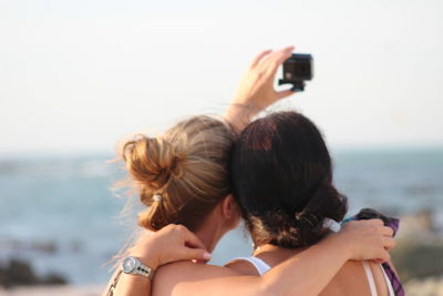 Rear view of senior woman photographing sea