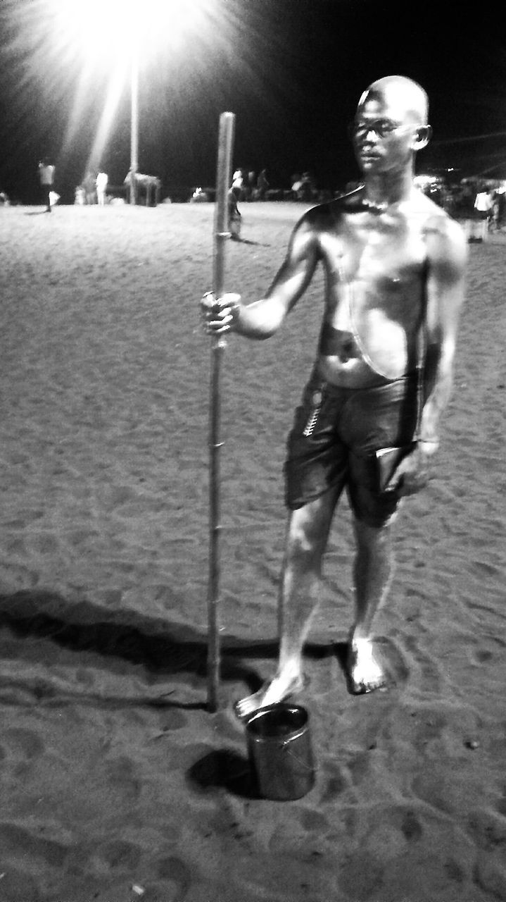 MAN STANDING ON BEACH AGAINST SKY