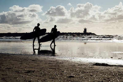 Silhouette men standing on beach against sky