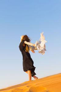 Woman with arms raised against clear sky