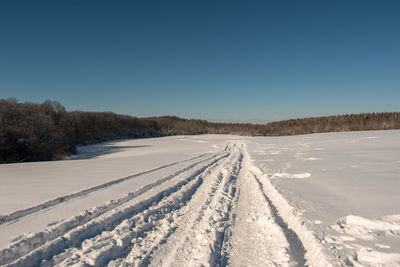 Scenic view of snow covered field against clear blue sky