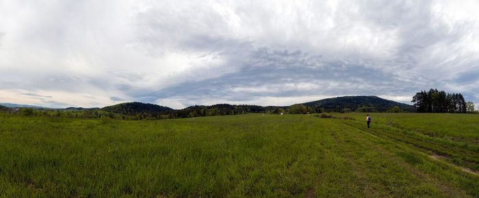  panorama of a person with backpack hiking in meadow field against hills near rabka to lubon wielki