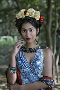 Portrait of young woman wearing tiara and dress standing in park