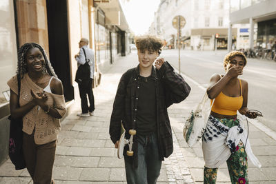 Portrait of teenage boy walking with friends on footpath