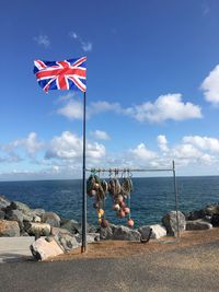 Flags on rocks at beach against sky