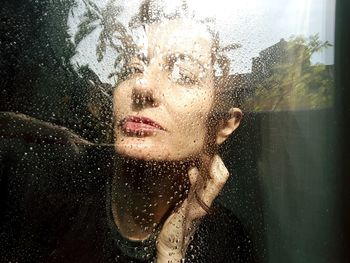 Portrait of woman with wet glass window in rainy season