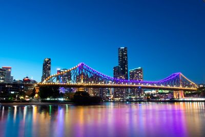 Illuminated bridge over river against sky at night