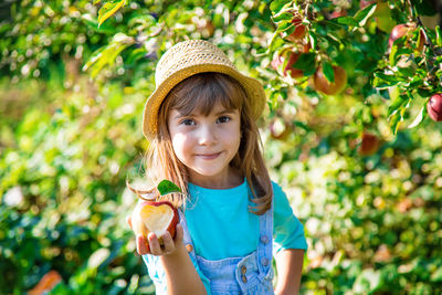 Girl wearing hat holding fresh apple