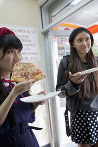Happy young woman enjoying a slice of pizza