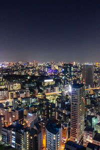 High angle view of illuminated buildings against clear sky at night
