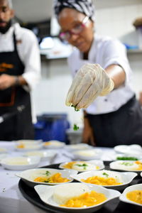 Mature woman garnishing food while standing in commercial kitchen