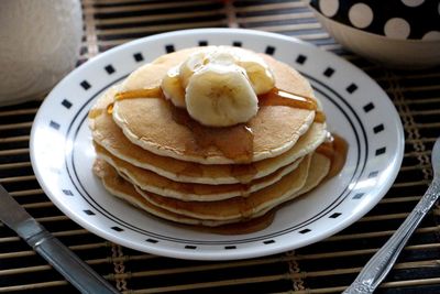 Close-up of pancakes with banana in plate on table
