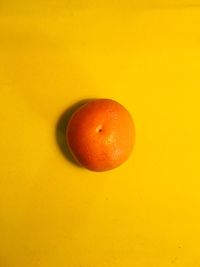 Directly above shot of orange fruit against yellow background
