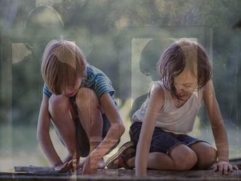 Double exposure of brother and sister playing and standing at window