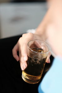 Cropped hand of person holding drink in glass