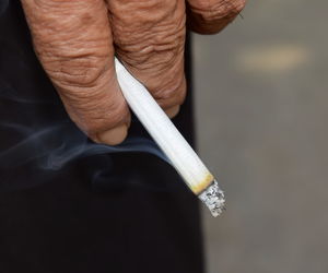 Close-up of hand holding burning cigarette outdoors