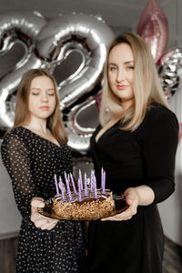 Beautiful young woman standing by cake