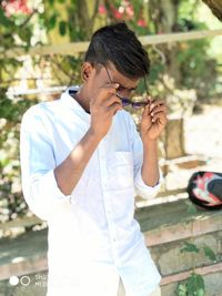 Young man holding camera while standing outdoors