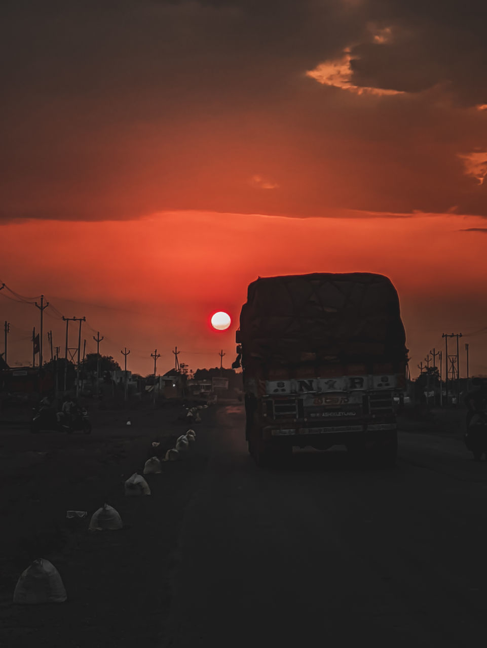 CAR ON STREET AGAINST ORANGE SKY