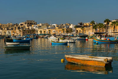 Traditional colorful luzzu fishing boats arriving and anchoring in marsaxlokk village harbor