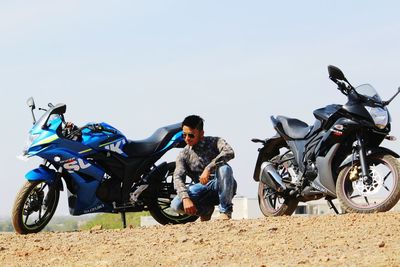 Man crouching amidst motorcycles on field