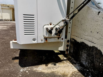 Close-up of machinery on wall by street in city