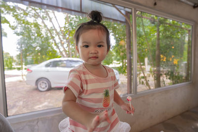 Portrait of cute girl standing by car window