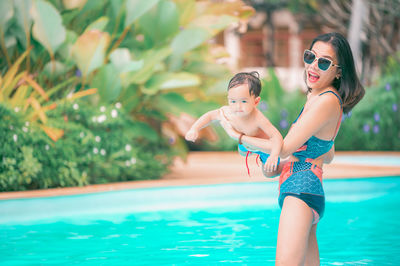 Smiling mother with son sitting by swimming pool