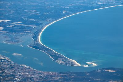 Aerial view of sea and snowcapped mountains against blue sky