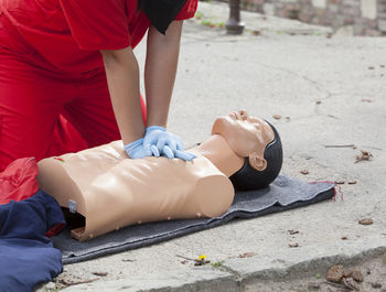 Midsection of paramedic performing cpr on mannequin