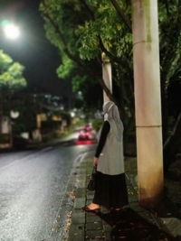 Man standing on street by tree